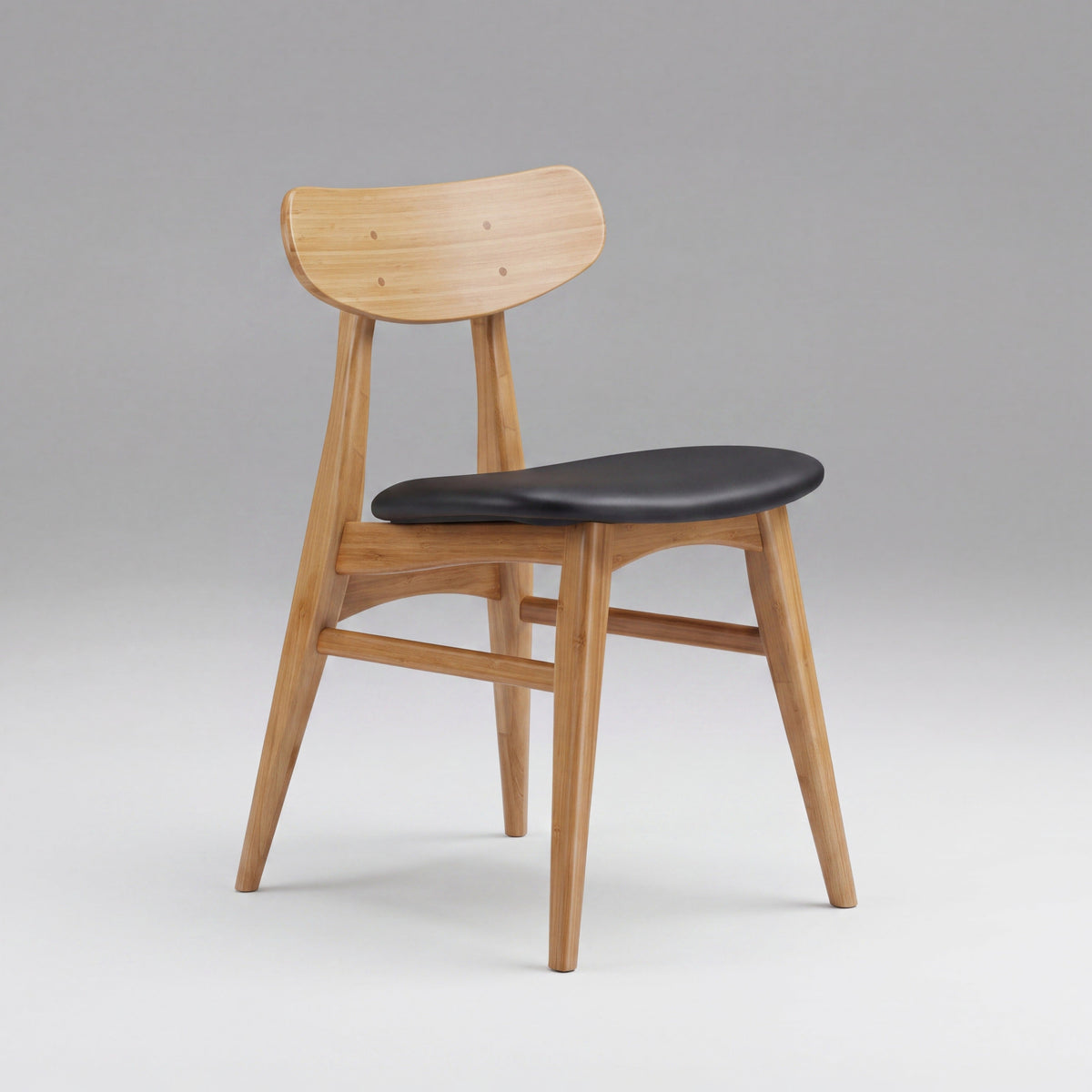 Greenington Cassia Dining Chair in Caramelized bamboo with a black leather seat, on a grey studio background, three-quarter view