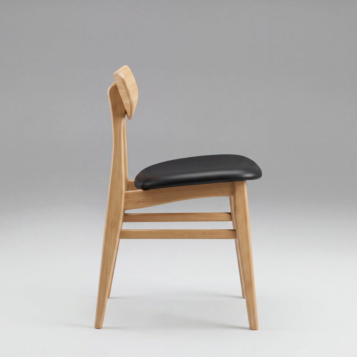 Greenington Cassia Dining Chair in Caramelized bamboo with a black leather seat, on a grey studio background, side view