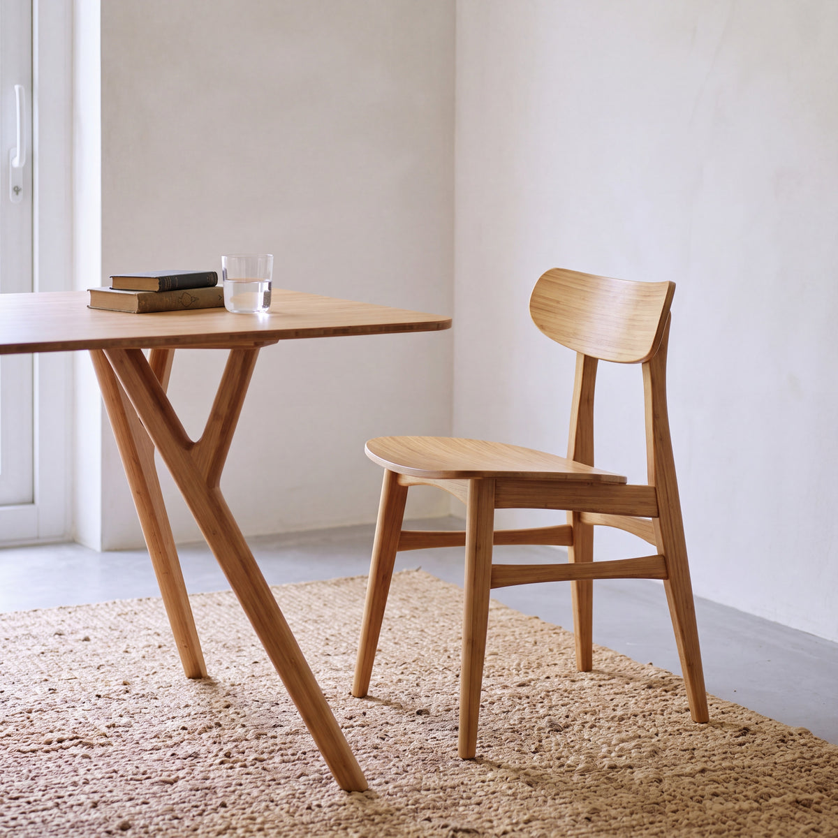 Greenington Cassia Dining Chair in Caramelized bamboo, styled at a rectangular table in a bright dining room, three-quarter view