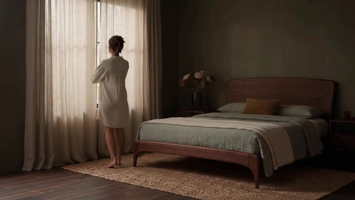 Greenington Zeva Platform Bed in Black Walnut bamboo, styled in a dark olive bedroom as a woman opens the curtains