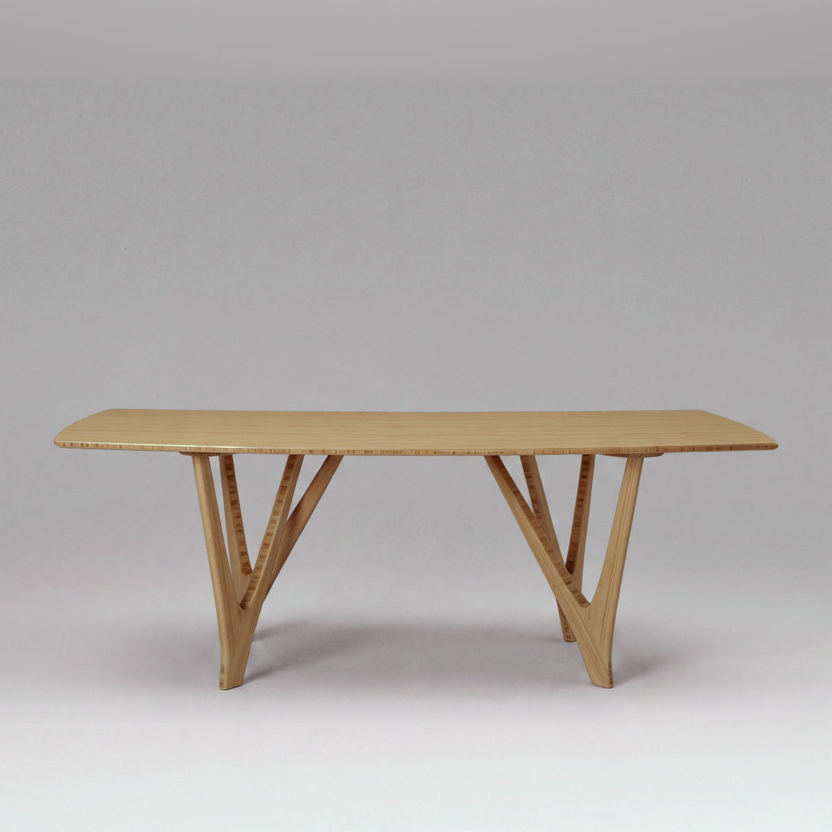 Greenington Vetra Dining Table in Caramelized bamboo, on a studio backdrop, front view