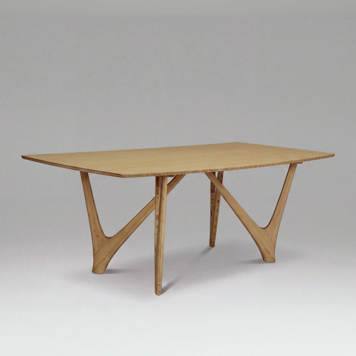 Greenington Vetra Dining Table in Caramelized bamboo, on a studio backdrop, three-quarter view