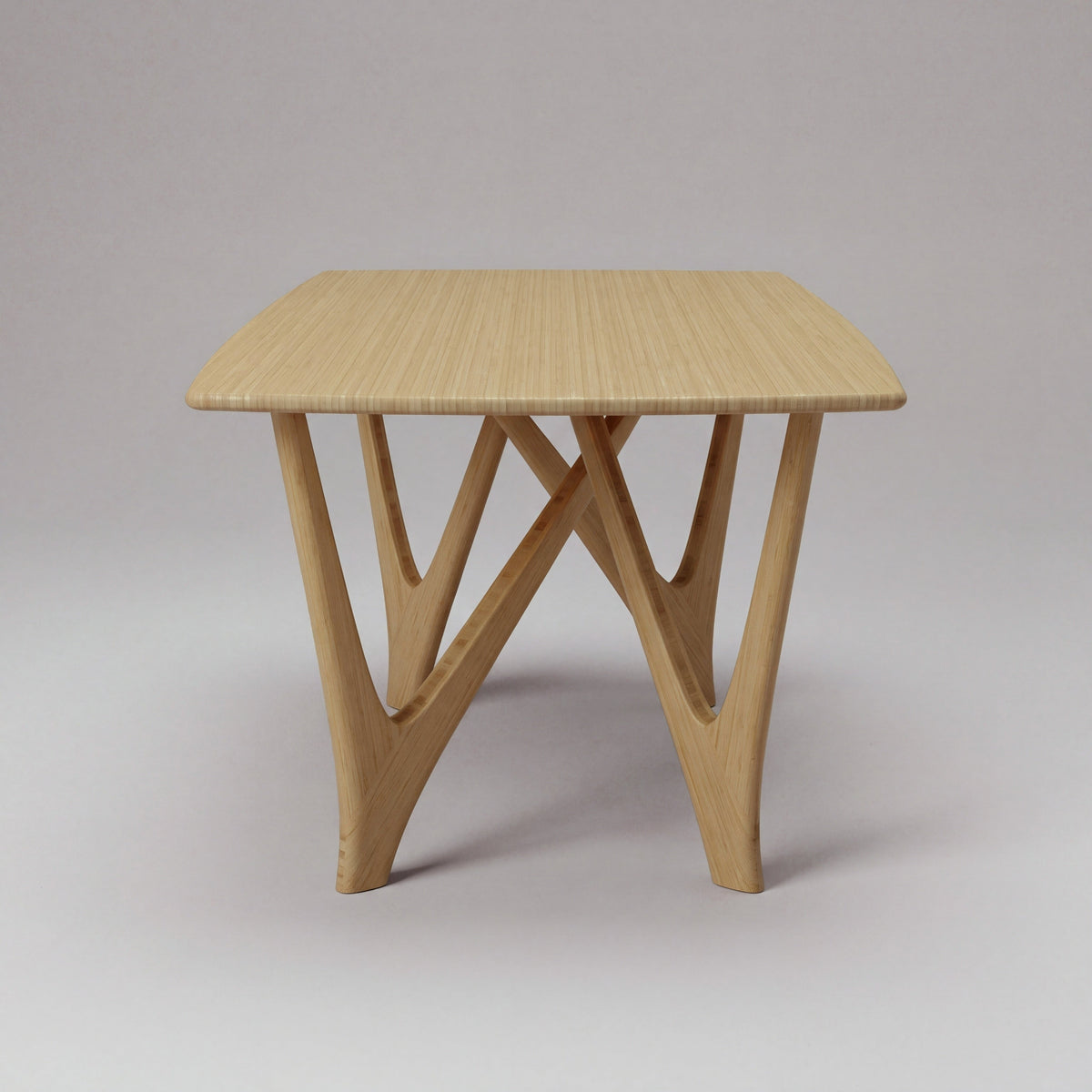 Greenington Vetra Dining Table in Caramelized bamboo, on a studio backdrop, end view